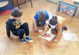 Lenka, Filip i Kuba układają papierowe puzzle.